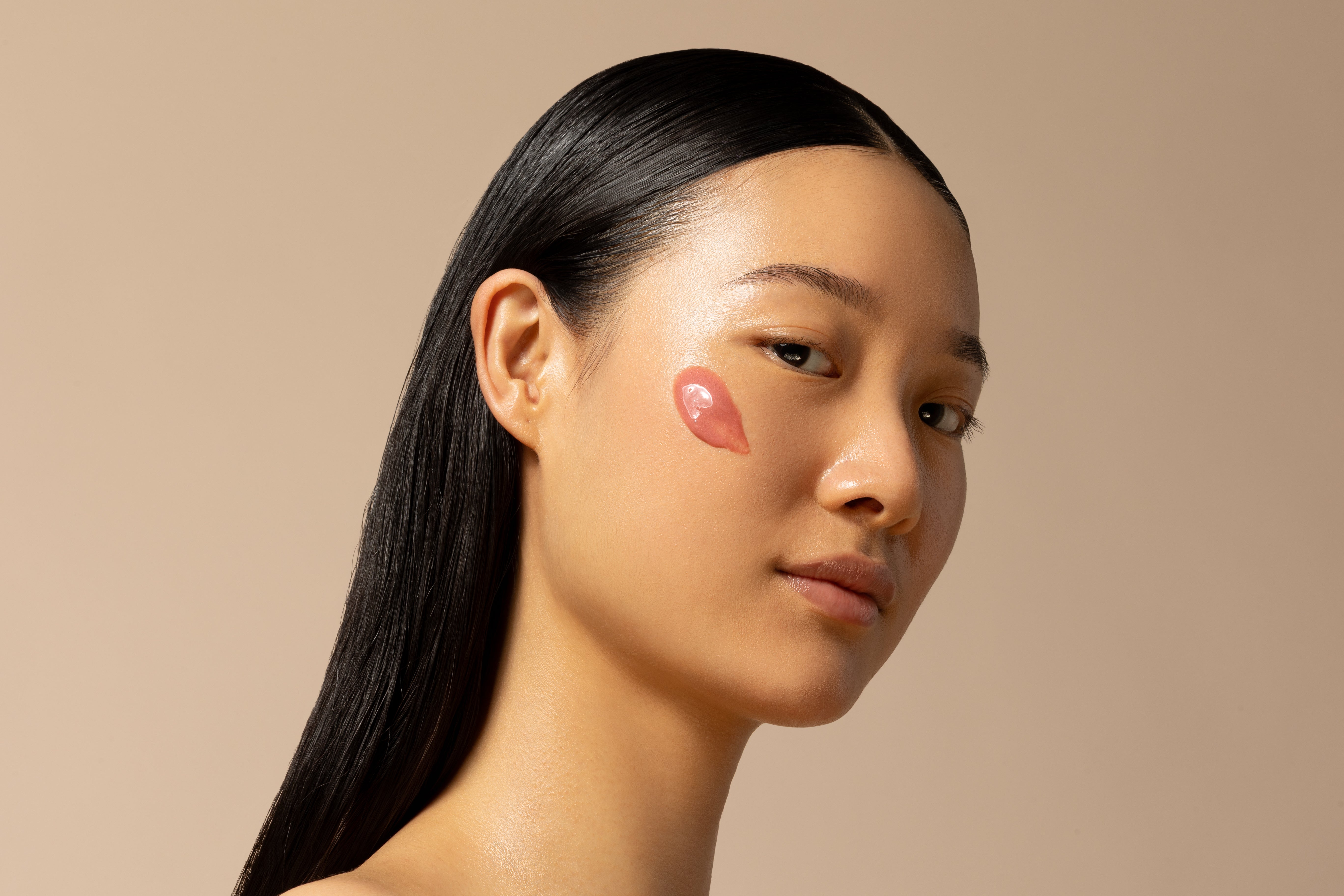 Woman with a patch on her cheek against a beige background